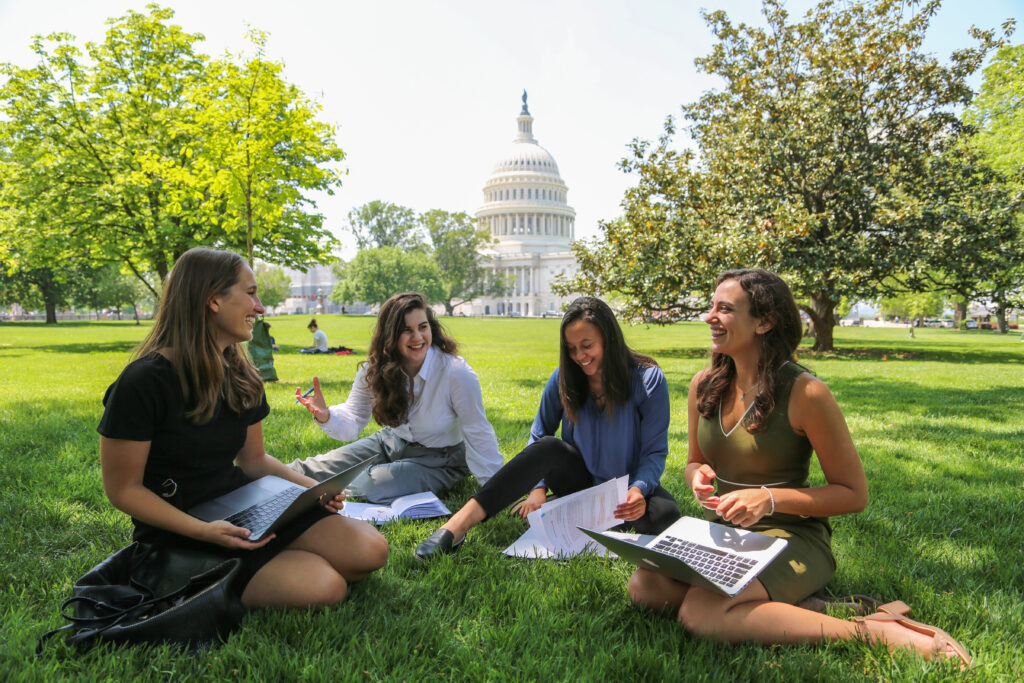 Image of Georgetown students sitting on a lawn in front of the Capitol building. 